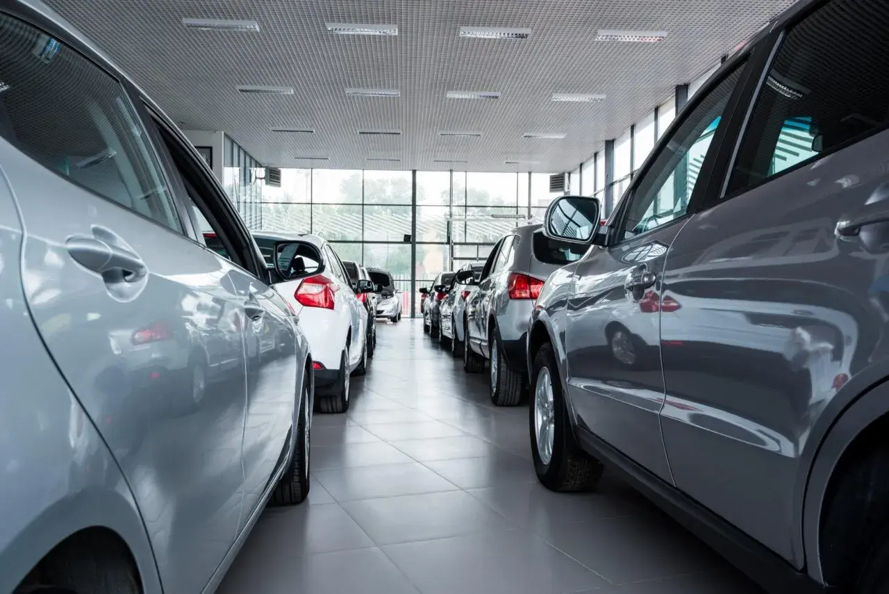 Auto km 0: cosa controllare. Diverse auto nuove in fila in un concessionario, pronte per essere visionate.