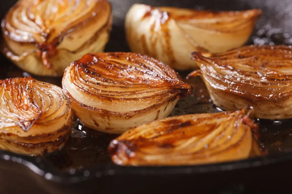 Cebolla caramelizada dorada y jugosa en una sartén.