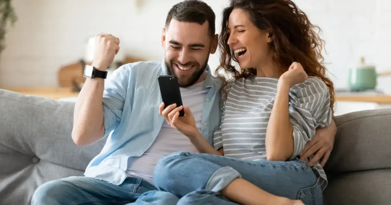 Para jak z liceum, zakochani, cieszą się z sukcesu, patrząc na telefon.