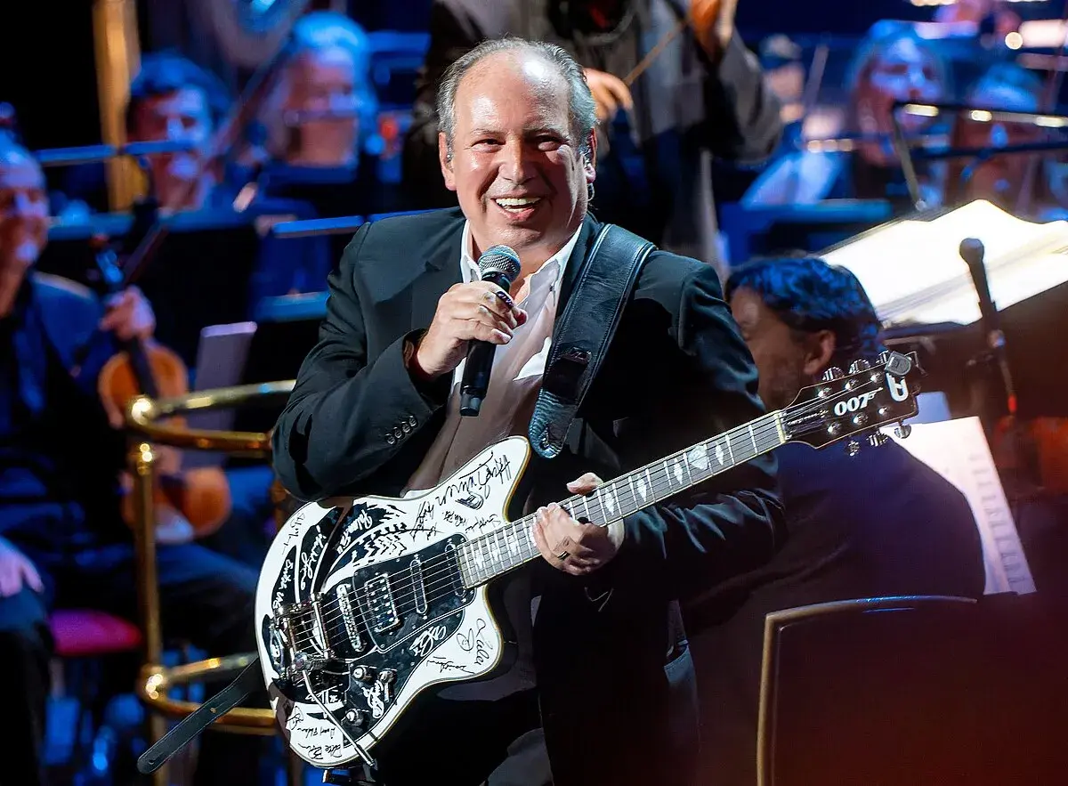 Hans Zimmer z gitarą, która brzmi jak ścieżka dźwiękowa do jego filmów. Uśmiechnięty kompozytor na scenie z orkiestrą.