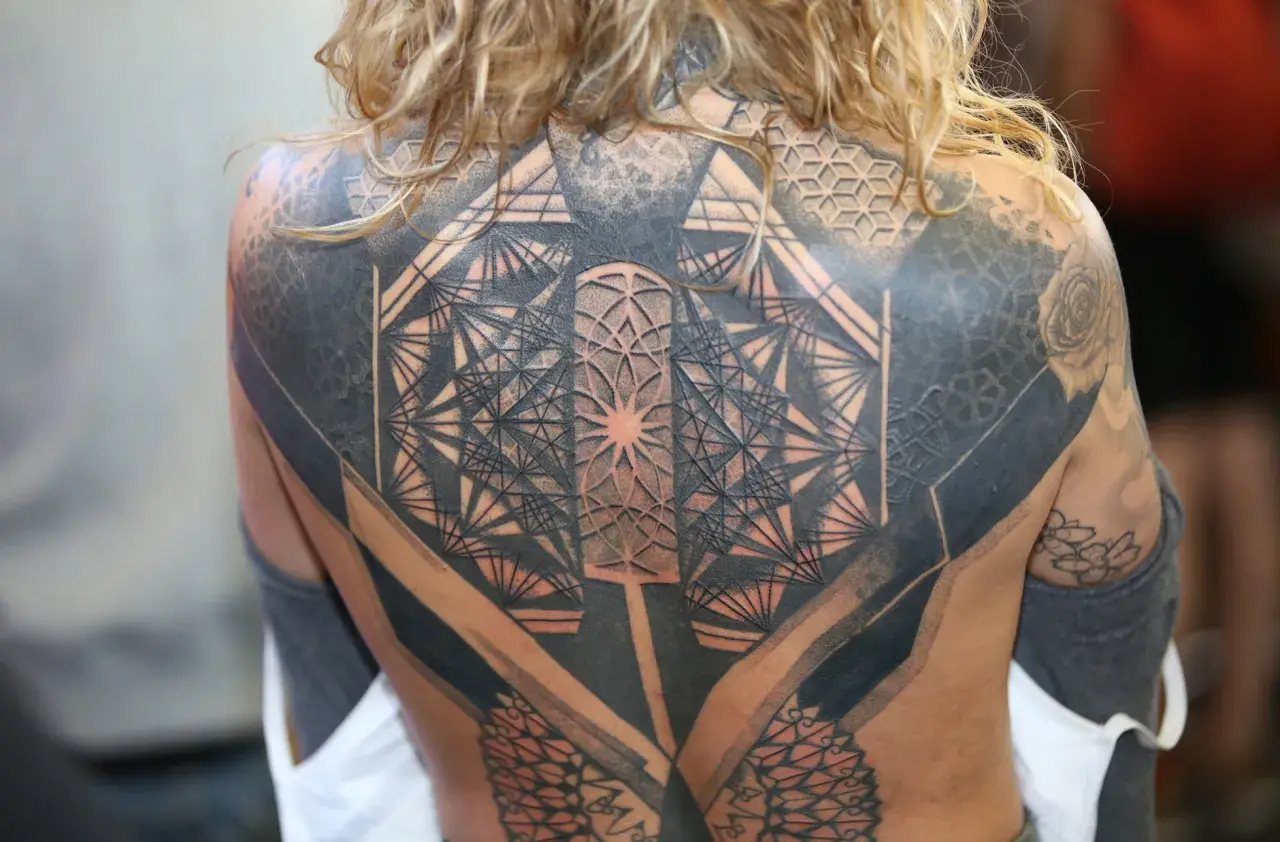 Niesamowity tatuaż 3d na plecach, pełen geometrycznych wzorów i cieniowania, tworzący iluzję głębi.