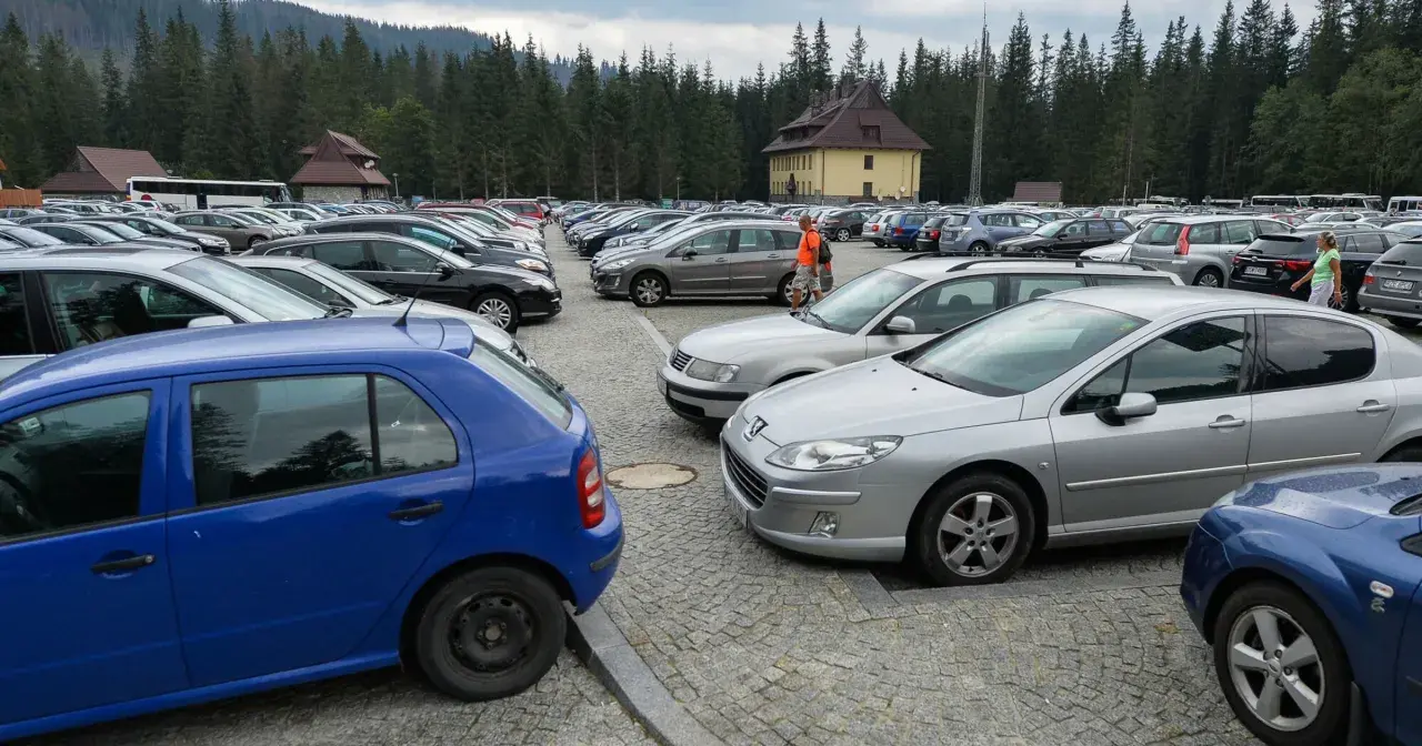 Duży parking samochodowy na Łysej Polanie na Słowacji, otoczony lasem.