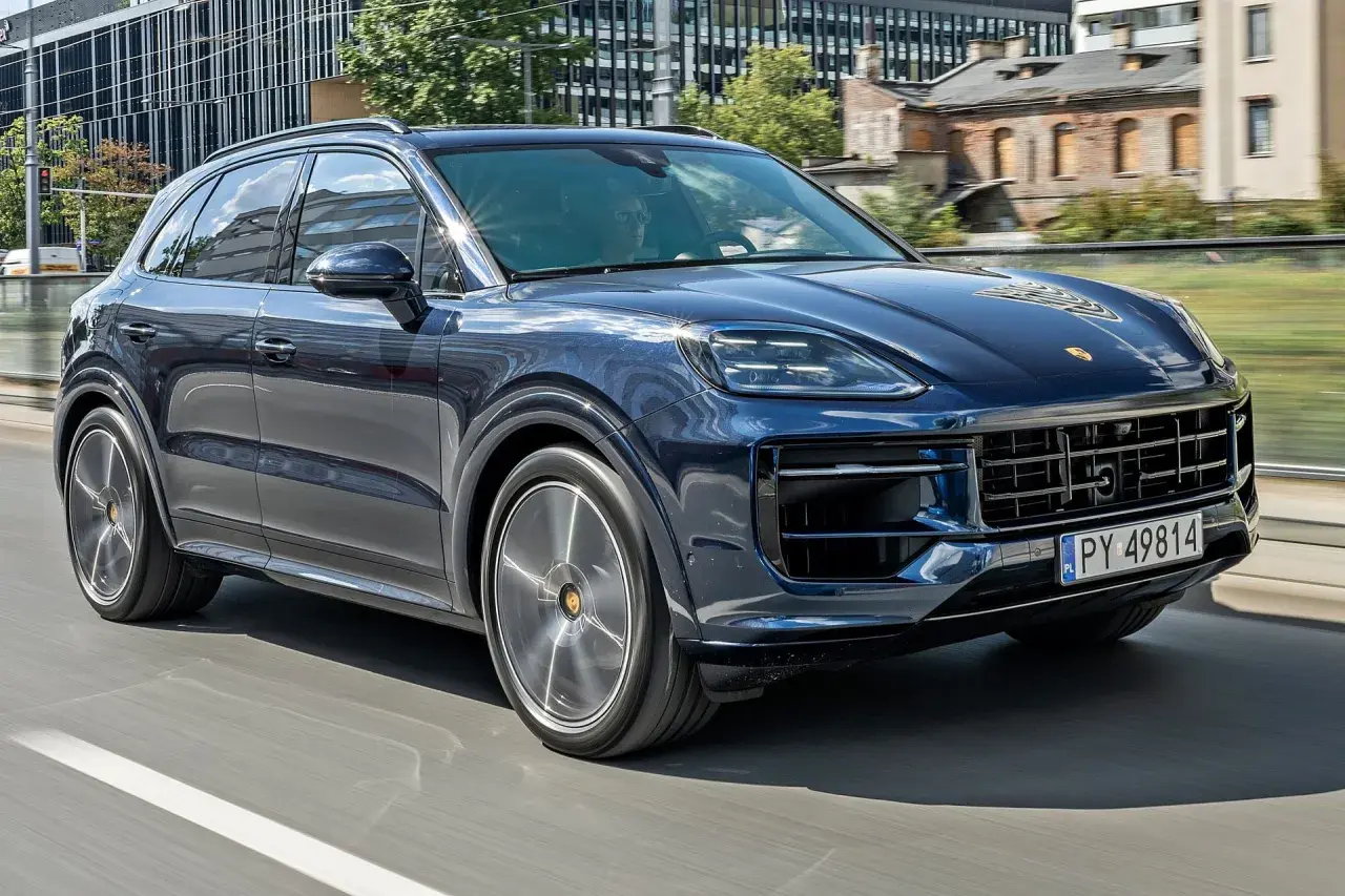 Ciemnoniebieski Porsche Cayenne jedzie po mieście. Sprawdź aktualną porsche cayenne cena.