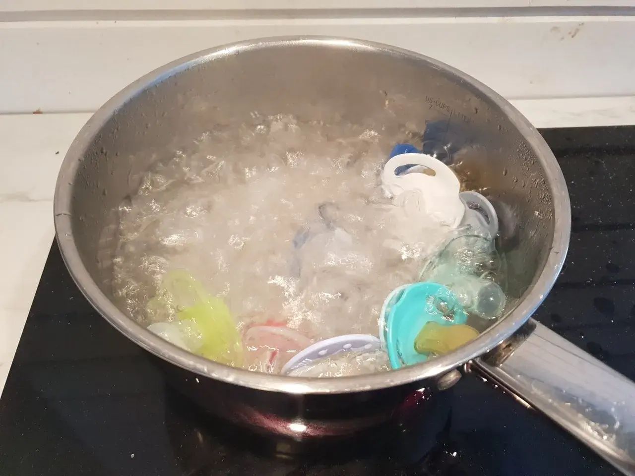 Flera nappar i olika färger kokas i en kastrull med bubblande vatten för att desinficera dem.
