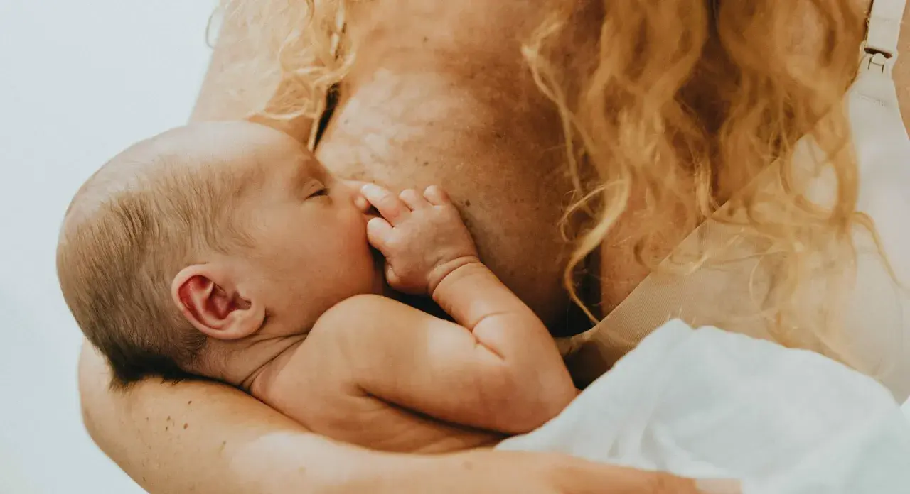 En bebis ammas, med handen vid munnen. En lugn stund för mamma var tredje timme.