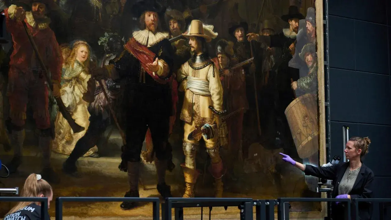 Restauratorin zeigt auf Rembrandts "die nachtwache maler", ein Meisterwerk der Malerei, das gerade untersucht wird.