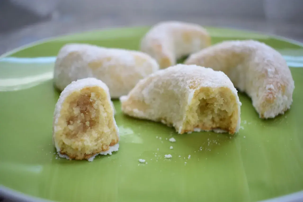 Petits gâteaux en forme de croissant, saupoudrés de sucre glace. Ces délices ressemblent à des cornes de gazelle, prêts à être dégustés.