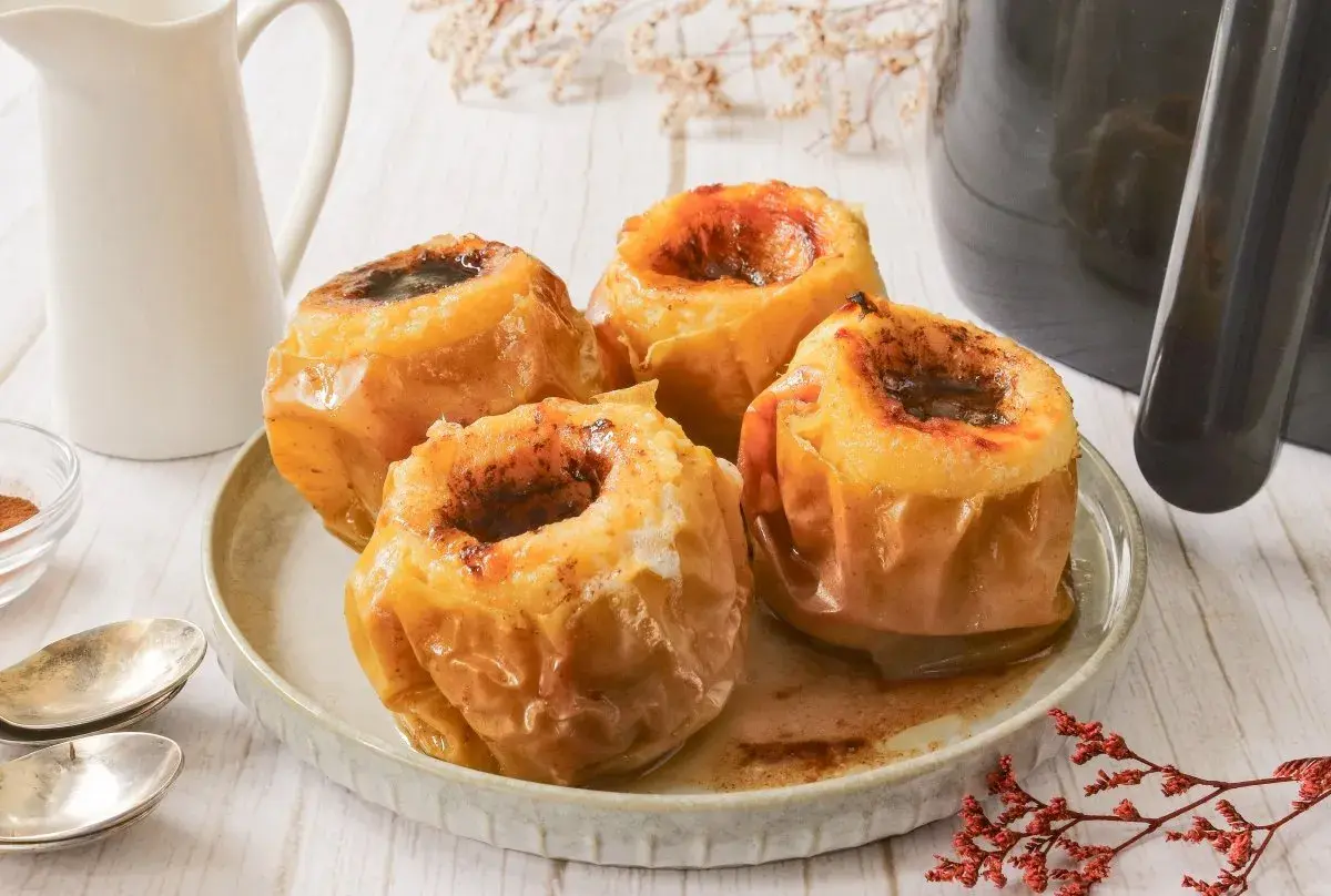 Cuatro deliciosas manzanas asadas en freidora de aire, con un relleno dulce y especiado, listas para disfrutar.