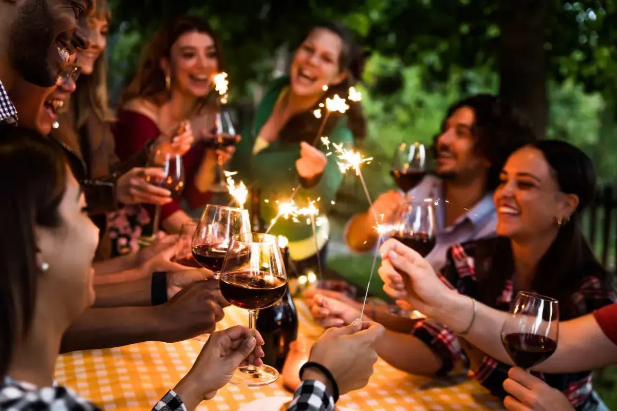 Amigos celebran un cumpleaños con vino y bengalas, disfrutando de momentos especiales. ¡Ideas geniales de cosas para hacer en tu cumpleaños con amigos!
