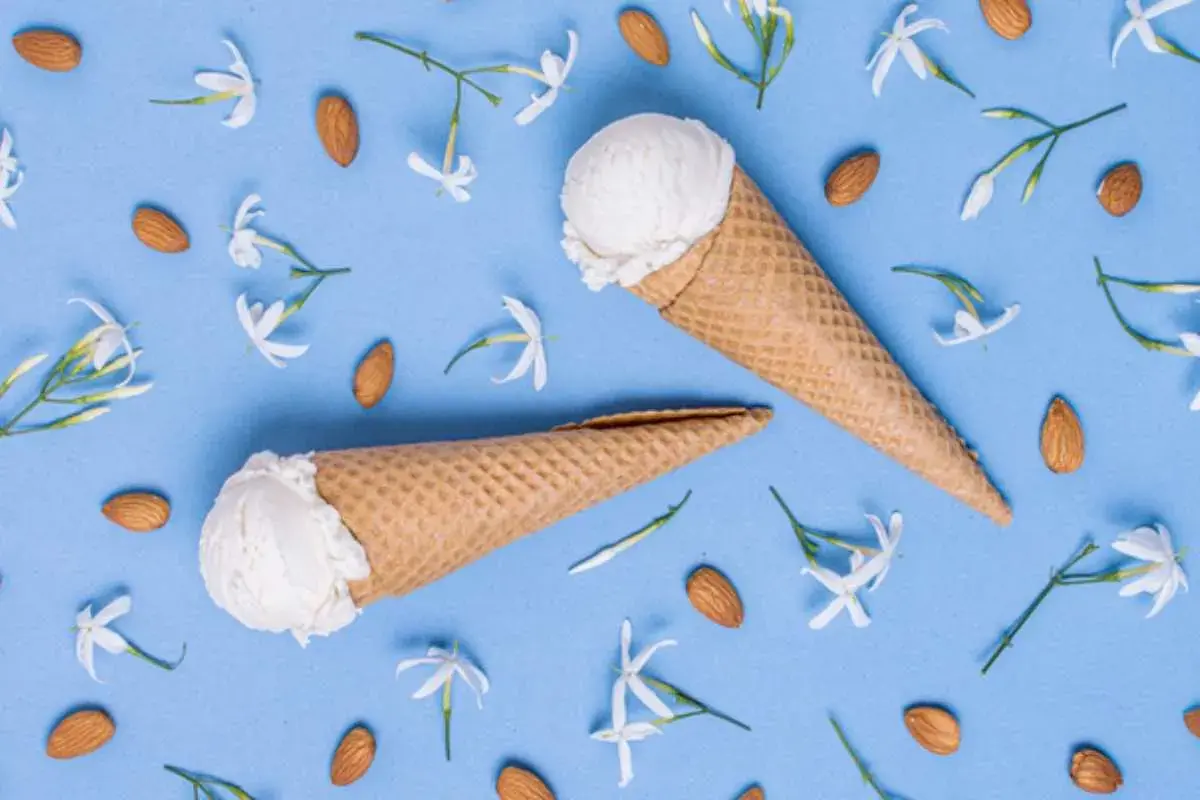 Due coni gelato al gelsomino, circondati da mandorle e delicati fiori bianchi su sfondo azzurro.