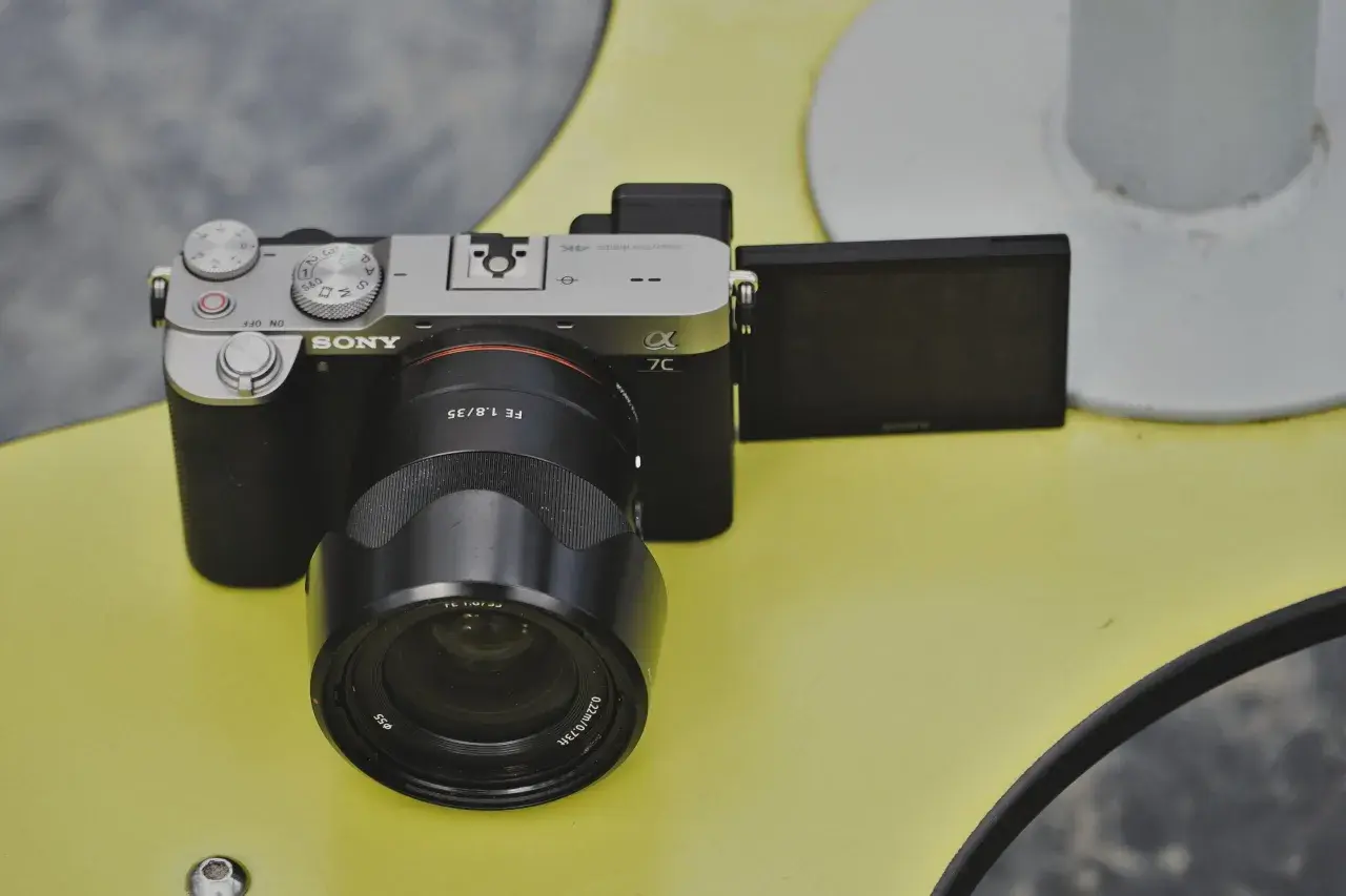 Aparat Sony a7c z obiektywem FE 1.8/35 na żółtym tle.