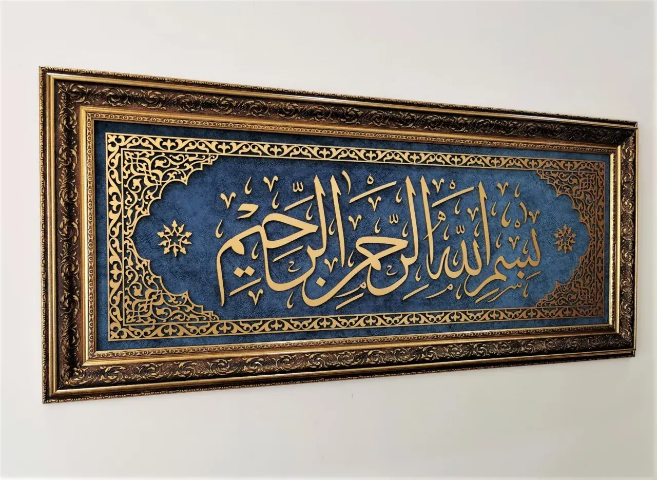 Złota kaligrafia "Bismillah" na granatowym tle, w bogatej, zdobionej ramie.