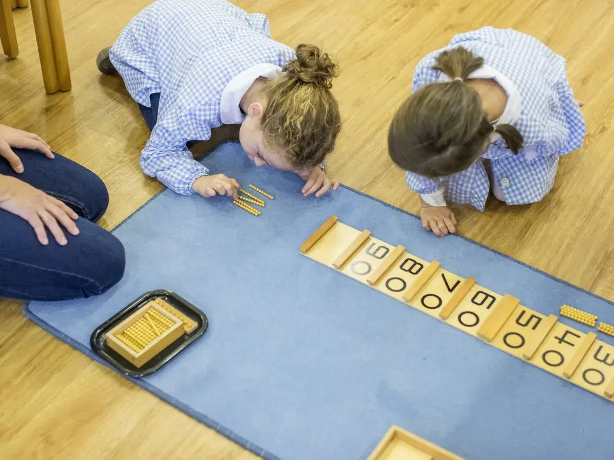 Niñas aprendiendo con el método Montessori en colegios, usando cuentas para sumar.