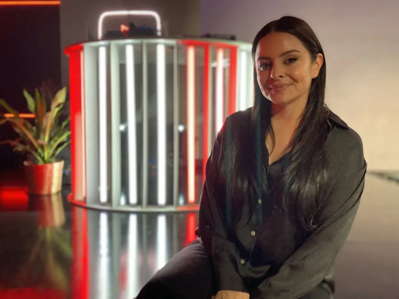 Michelle Kadir ler framför en ljusinstallation med röda och vita rör.