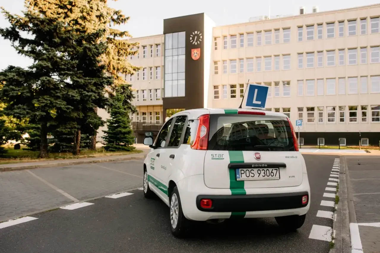 Biały Fiat Panda z zielonym pasem i literą "L" na dachu, gotowy do nauki jazdy. To auto jest kluczowe, gdy zastanawiasz się, co jest potrzebne do odbioru prawa jazdy.