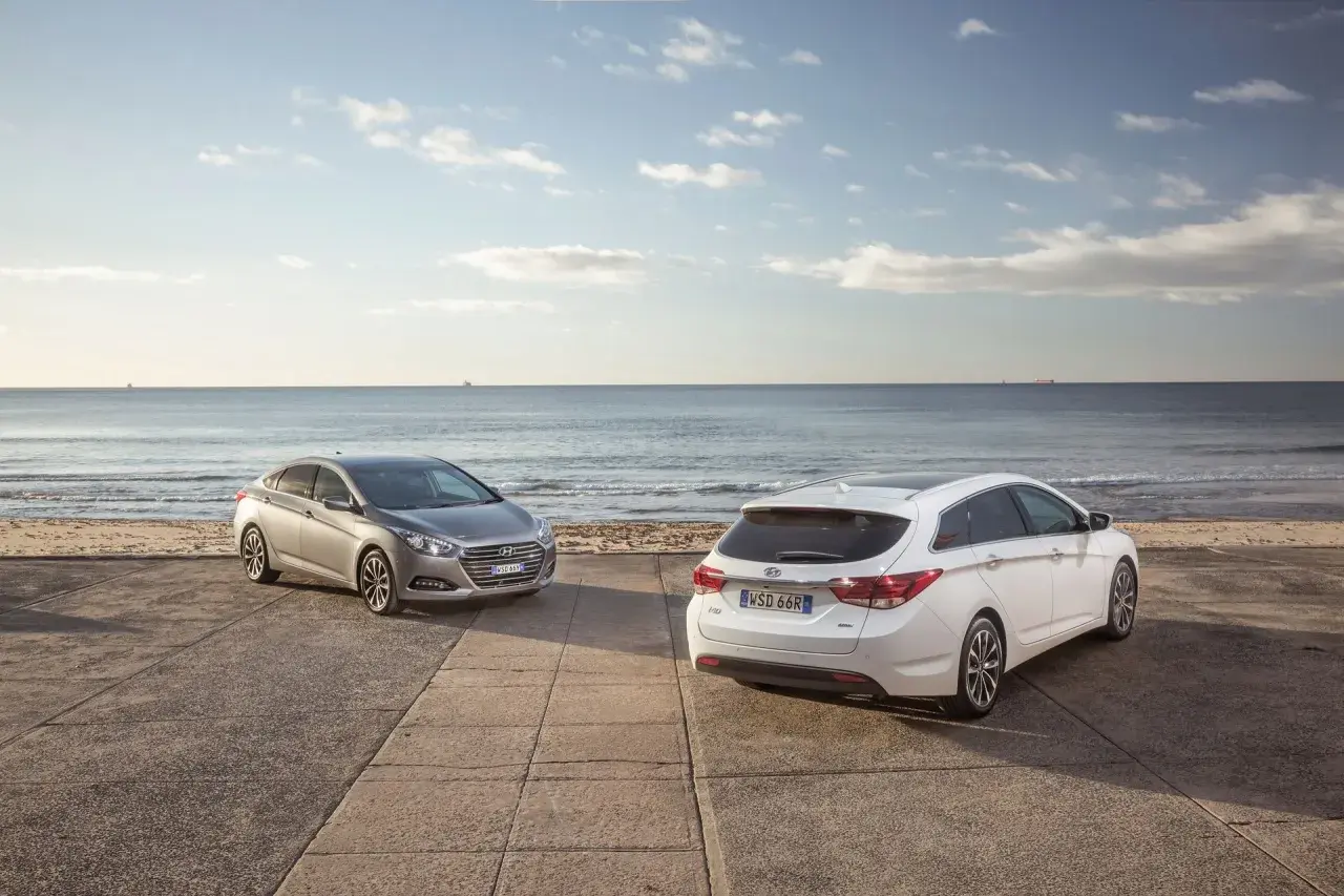 Dwa Hyundai i40, sedan i kombi, stoją nad brzegiem morza. Wiele pozytywnych hyundai i40 opinie potwierdza ich wszechstronność.