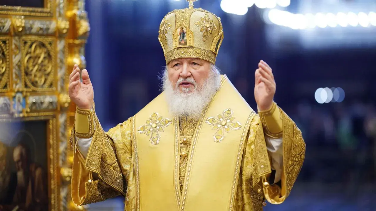 Patriarch Kyrill in golden vestments and crown, raising hands in blessing.