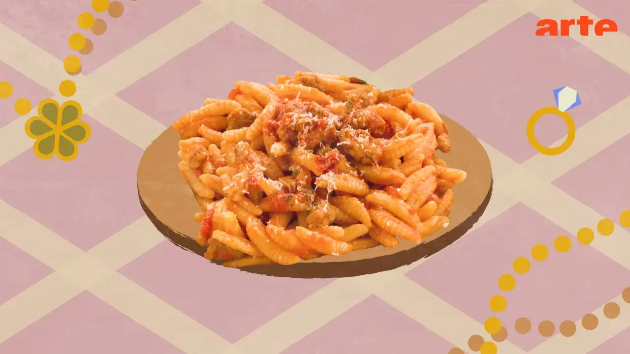 Un plat de malloreddus alla campidanese, pâtes traditionnelles sardes, servi sur une assiette dorée.