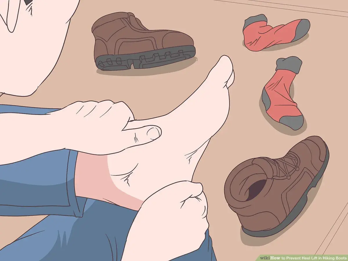 A person checks their foot, surrounded by hiking boots and socks, to prevent walking boots rubbing above the ankle.