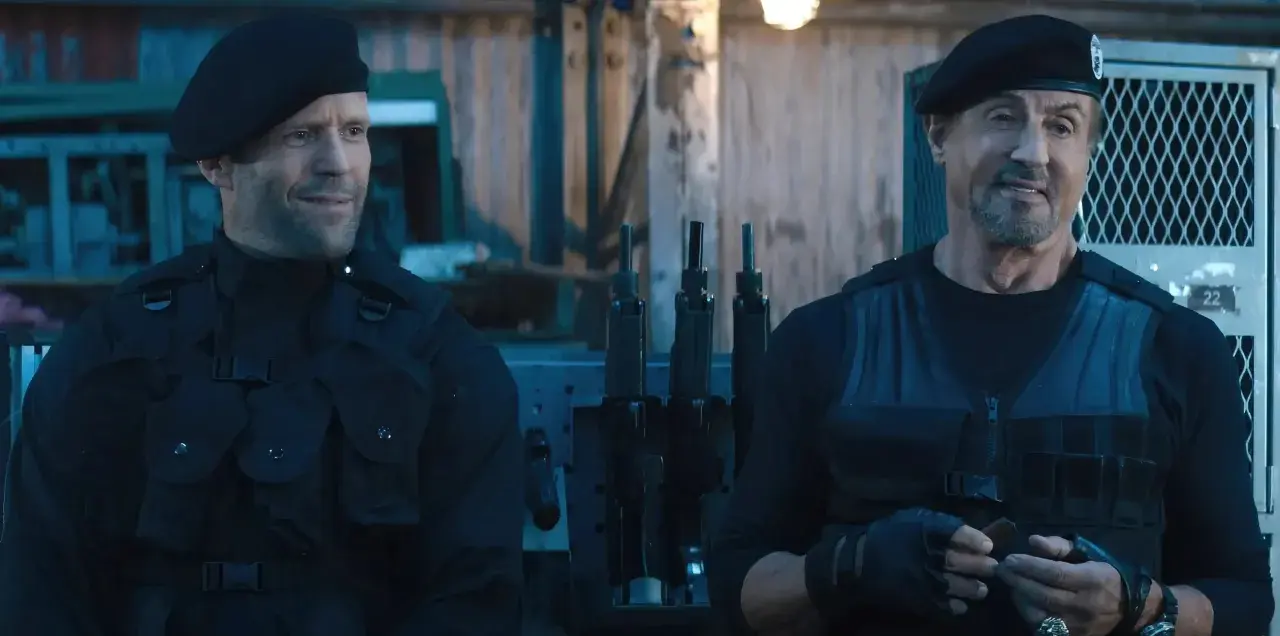Jason Statham i Sylvester Stallone w czarnych beretach i kamizelkach taktycznych, gotowi do akcji w filmie "Niezniszczalni 5".