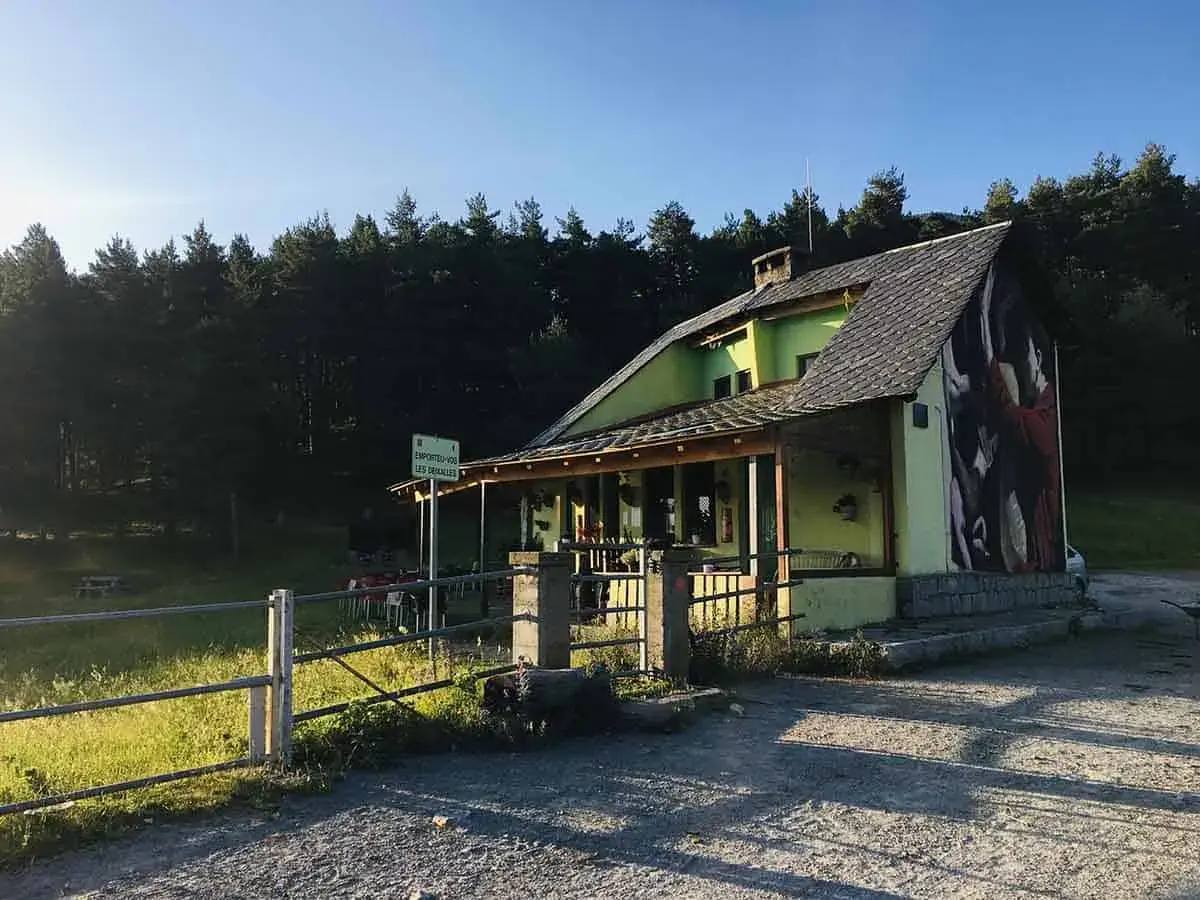 El refugi Serrat de les Esposes, un refugio acogedor rodeado de pinos, con un mural artístico en su fachada.