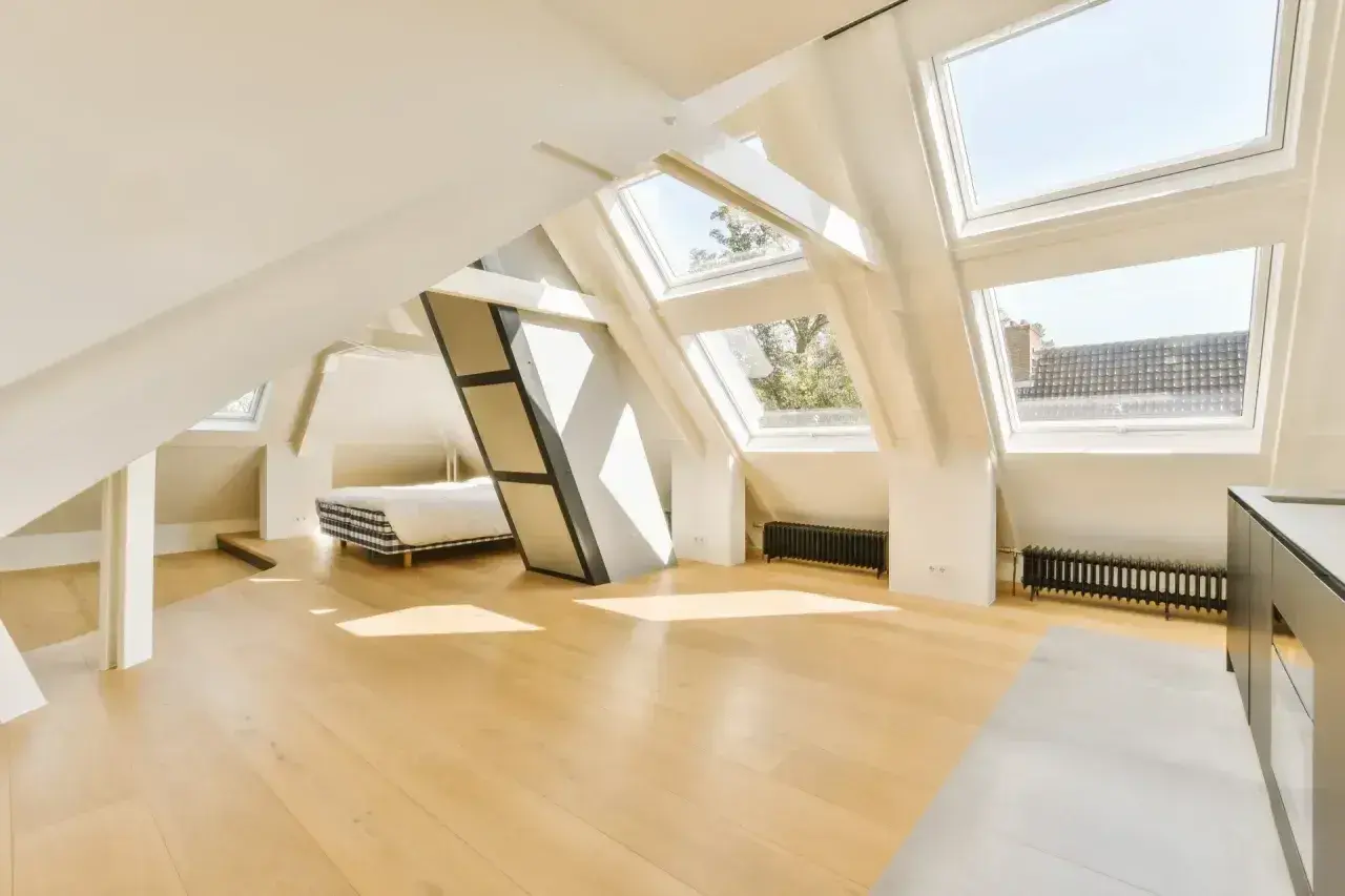 Jasne, oto propozycja:

Jasne poddasze z oknami dachowymi, łóżkiem i drewnianą podłogą. Idealne miejsce na adaptację poddasza bez zgłoszenia, tworząc przytulną przestrzeń.