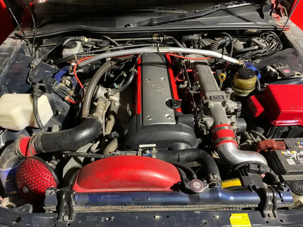 Silnik 2JZ-GE z turbosprężarką w Toyota Mark II. Widoczny czerwony filtr stożkowy i metalowe przewody dolotowe.