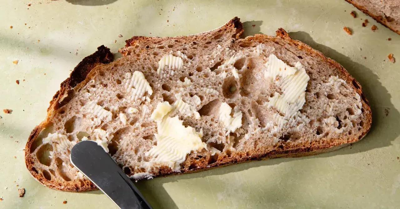 Tranche de pain de campagne, généreusement beurrée, prête à être dégustée. Une invitation à la simplicité et au bon goût.