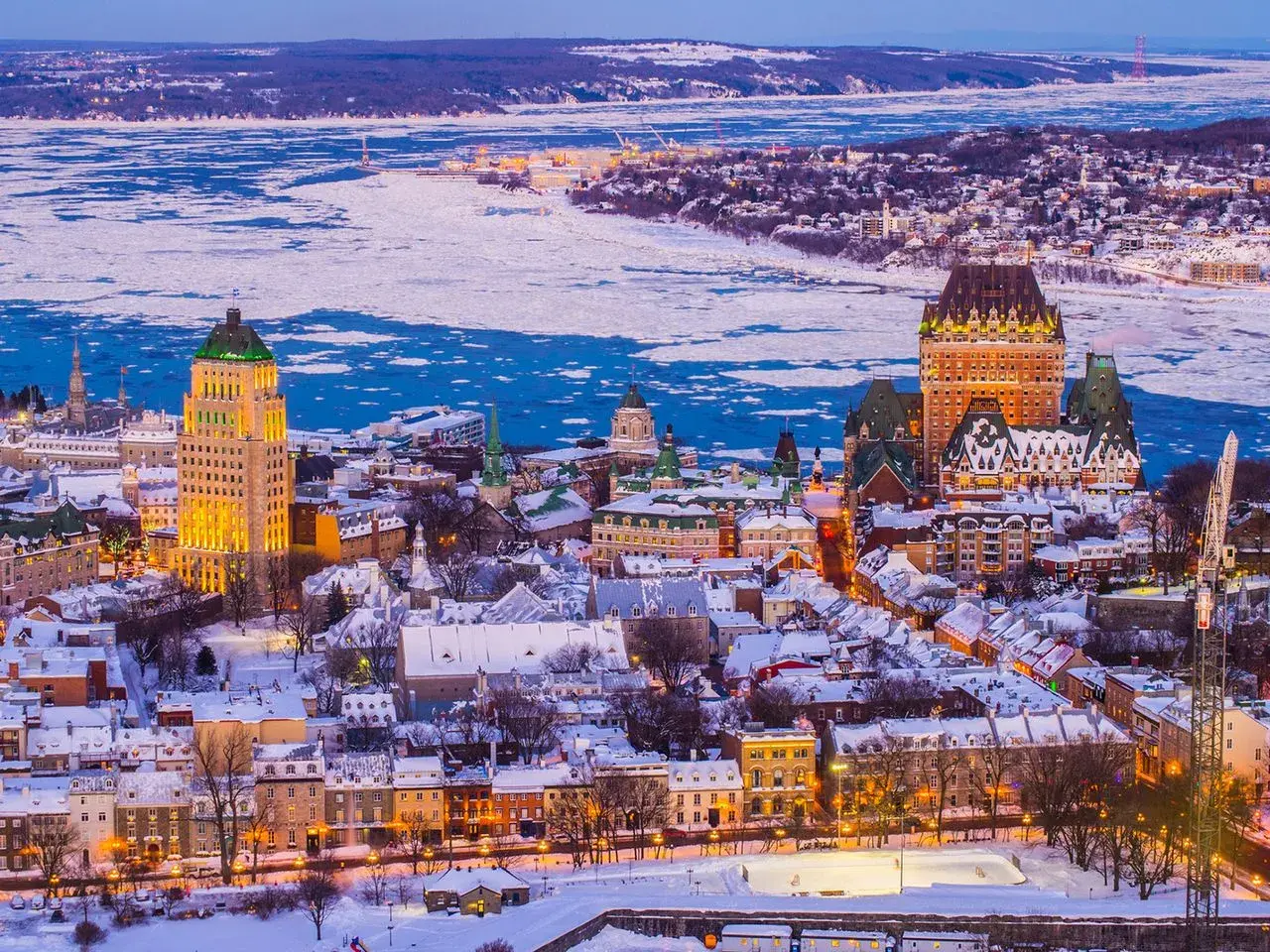 Quebec Winter: Eisbedeckter Sankt-Lorenz-Strom und schneebedeckte Dächer der Altstadt, beleuchtet vom Abendlicht.