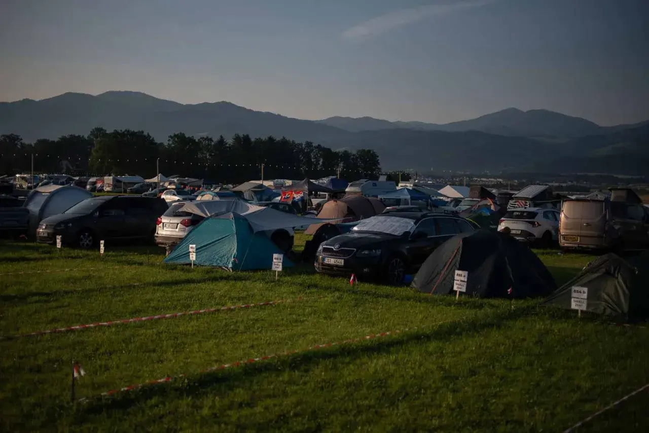 Rozległe pola namiotowe Austria, pełne namiotów i samochodów, z górami w tle.