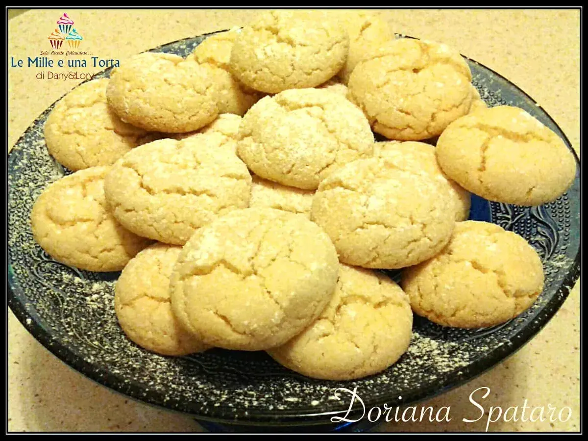 Biscotti con farina di mandorle, dorati e friabili, adagiati su un piatto scuro.