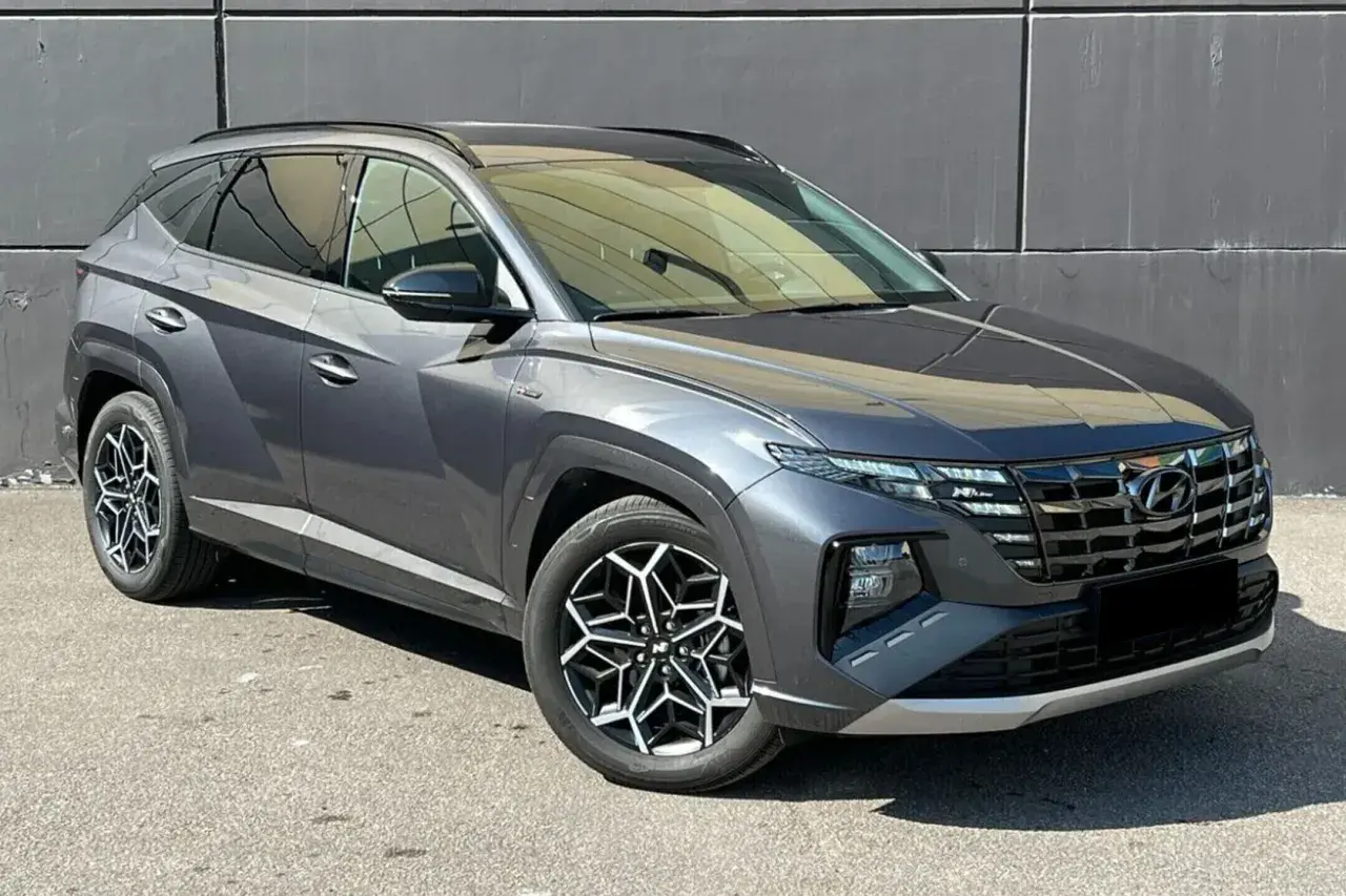 Szary Hyundai Tucson, jeden z najnowszych hyundai suv modele, z charakterystycznymi felgami i nowoczesnym designem, zaparkowany na tle szarej ściany.