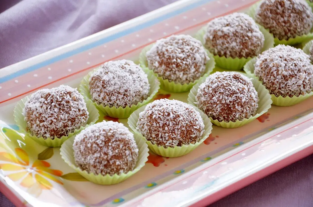 Deliziosi dolci di cocco, palline golose ricoperte di cocco grattugiato, disposte su un vassoio colorato.