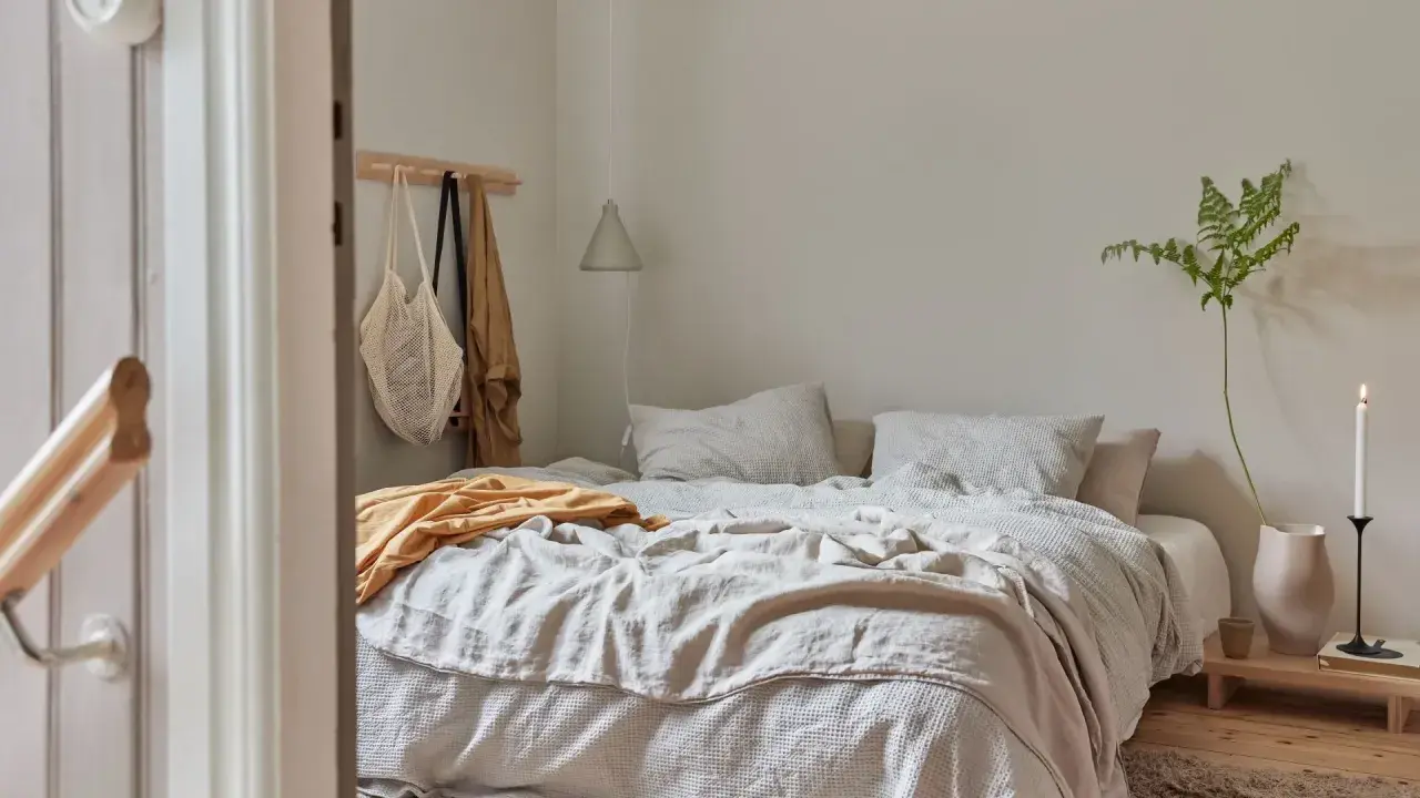 Sovrum med en bäddad säng i olika nyanser av beige. En gul filt ligger överst. Frågan "hur blandar man beige" besvaras här med en lugn och harmonisk inredning.