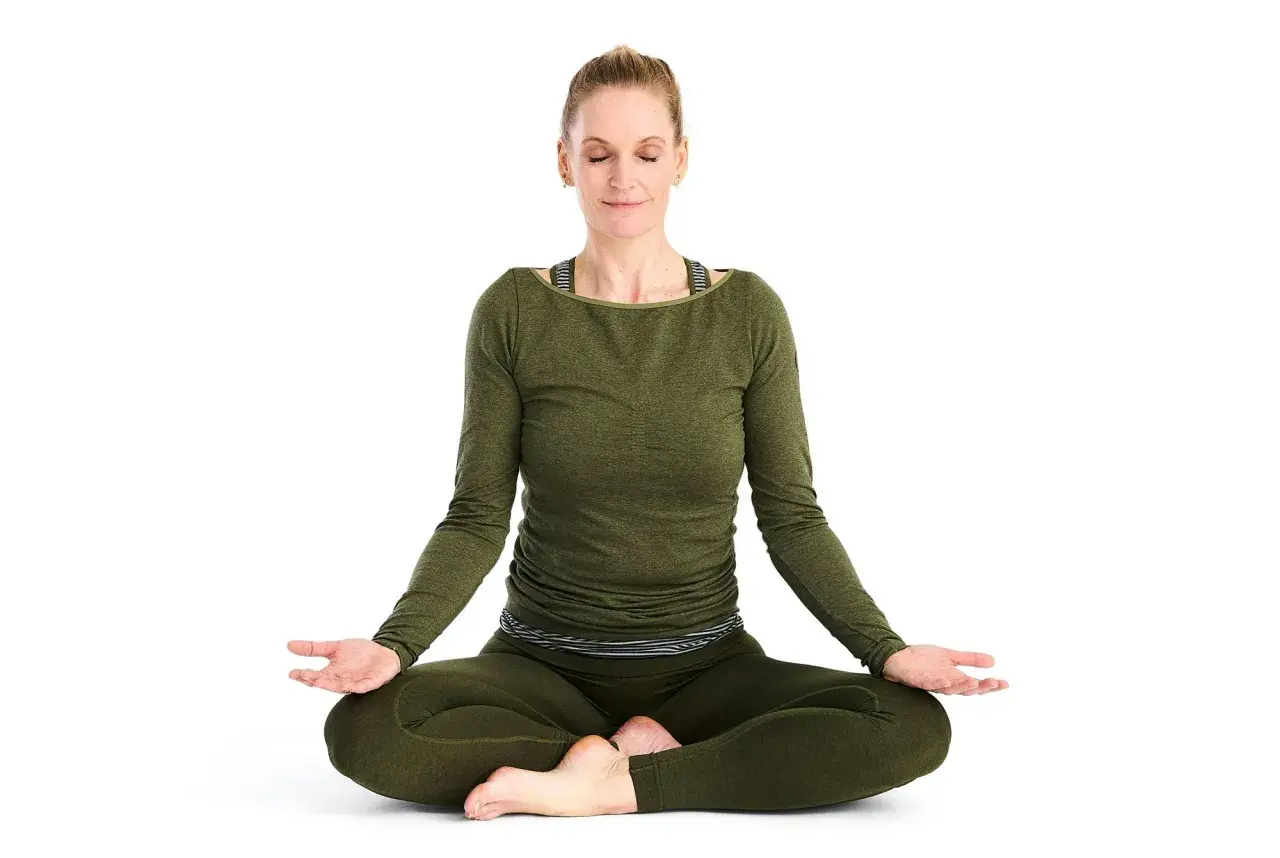 Kvinna i meditationsställning, fokuserad på breath work.