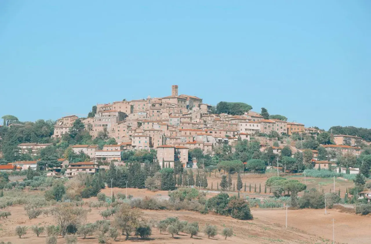 Panoramica di Casale Marittimo, un borgo medievale toscano arroccato su una collina, con case in pietra e tetti rossi, circondato da ulivi e cipressi.