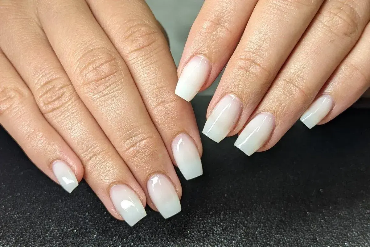 Mains aux ongles blancs laiteux, d'une douceur infinie. Une manucure parfaite pour un look épuré.