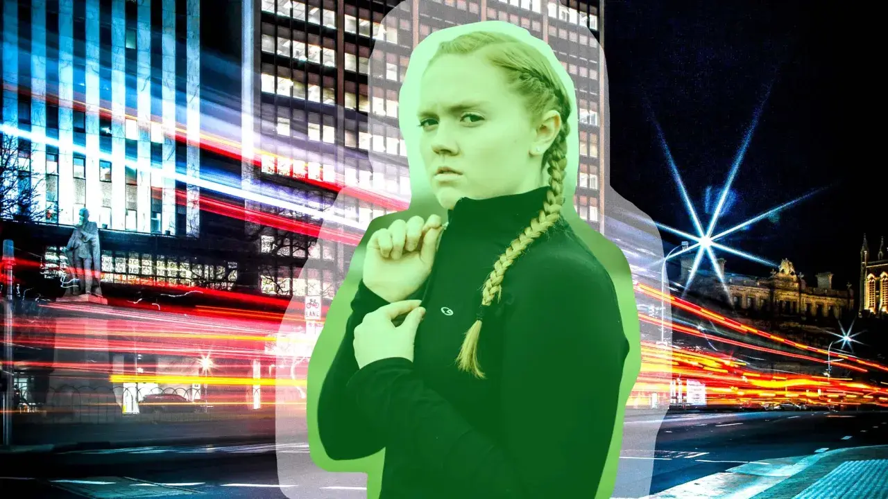 En ung kvinna med flätat hår ser misstänksam ut mot bakgrunden av en stad i rörelse. Kanske känner hon **avundsjuka på jobbet** när hon ser andras framgångar.