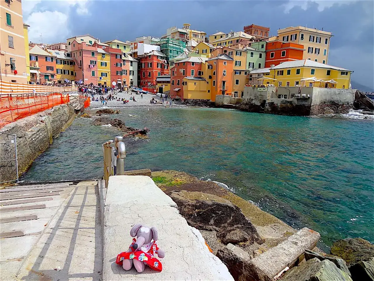 Une peluche attend sur les marches menant à la mer turquoise. Les maisons colorées de Boccadasse invitent à découvrir que faire à Gênes.