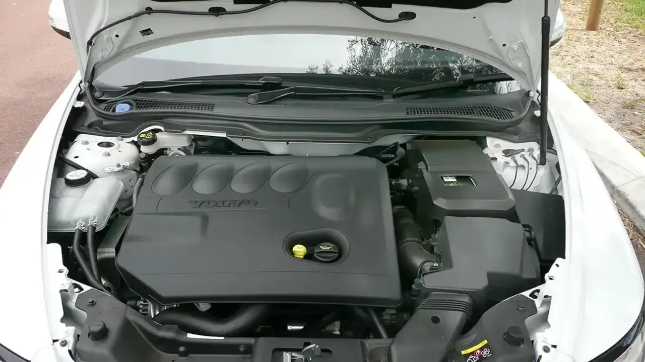 Silnik Volvo V50 2.0D z otwartą maską. Widoczna czarna pokrywa silnika z logo Volvo.
