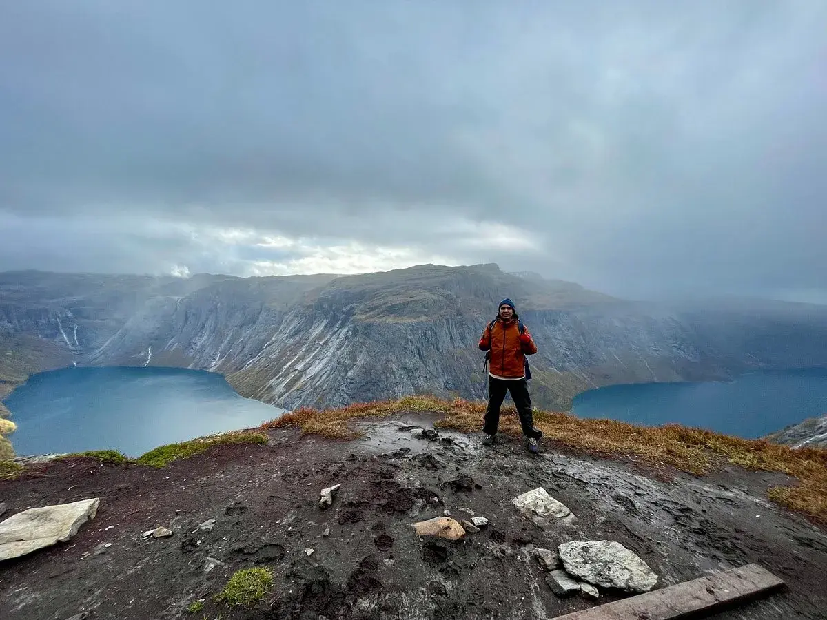 Man på en klippa med en sjö och berg i bakgrunden. En lyckad trolltunga vandring!