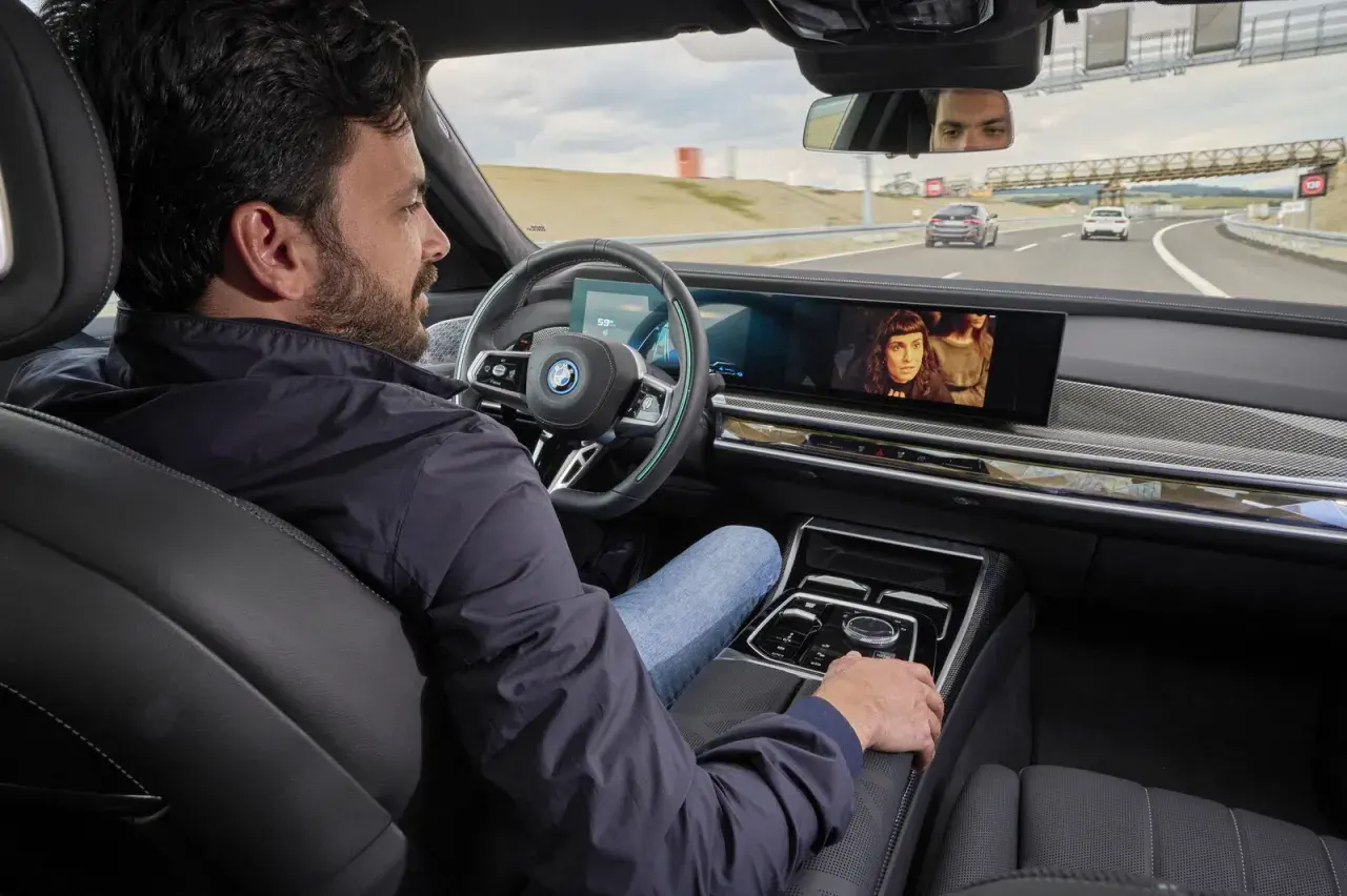 Uomo rilassato in auto, guarda un film mentre il sistema di **traffic jam assist** gestisce la guida in coda.