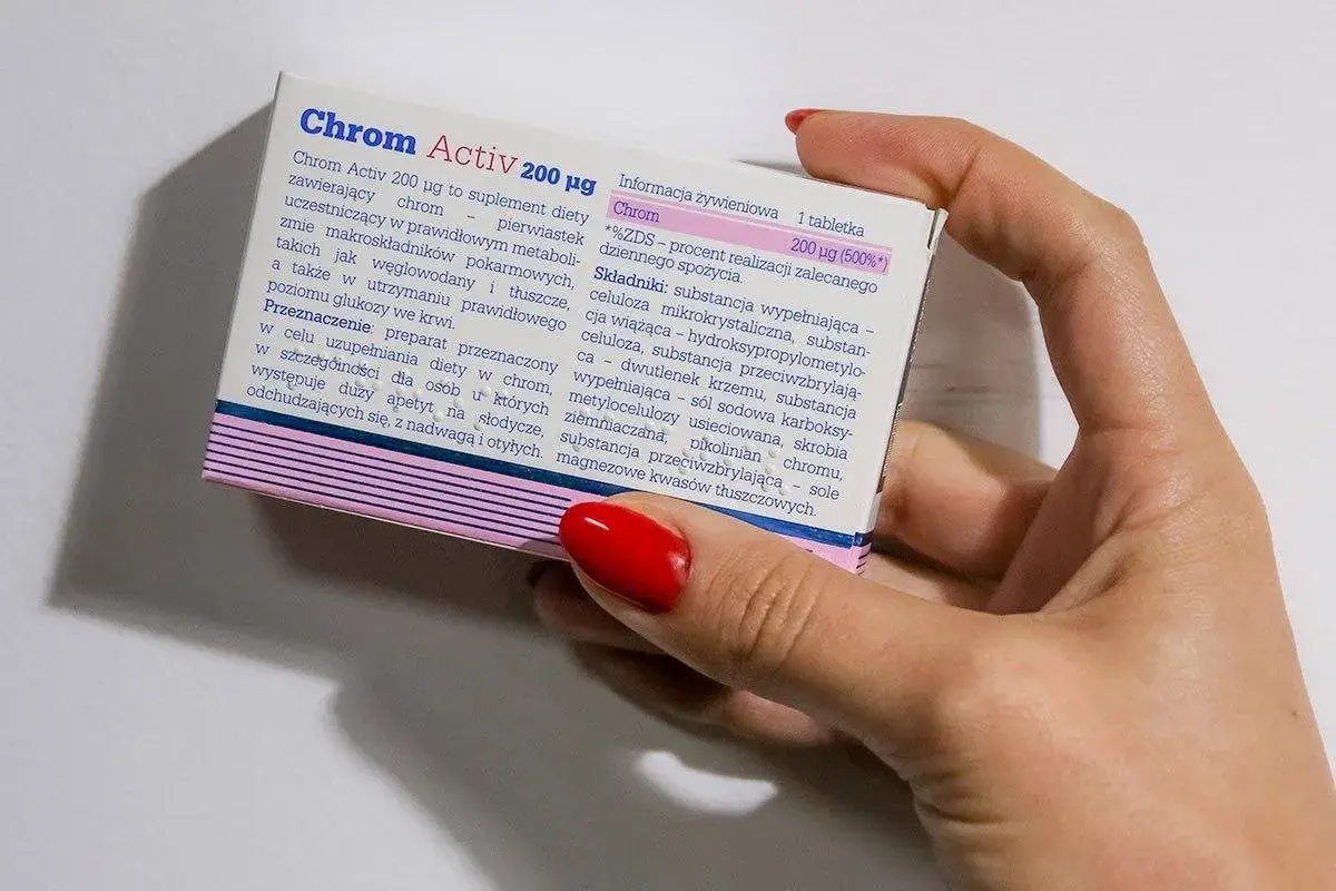 Dłoń trzyma opakowanie suplementu diety Chrom Activ 200 µg, który zawiera chrom.