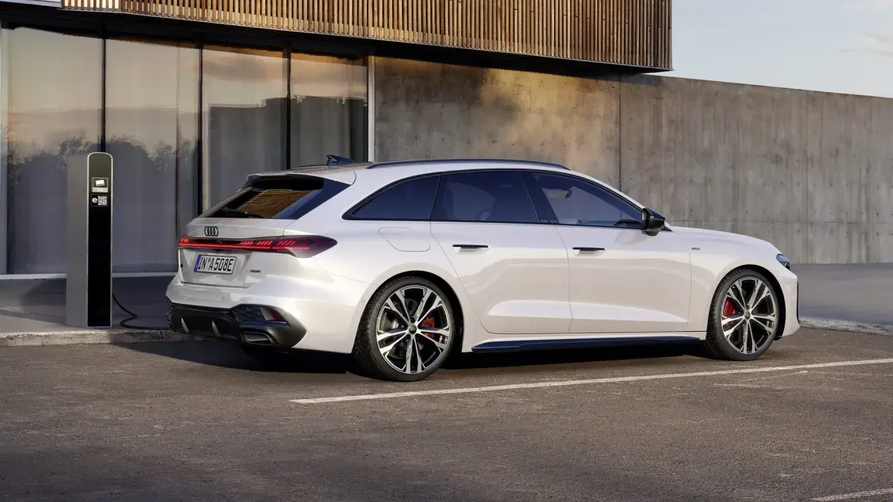 Vit Audi A5 hybrid laddas vid en laddstation. Modern design möter hållbarhet.