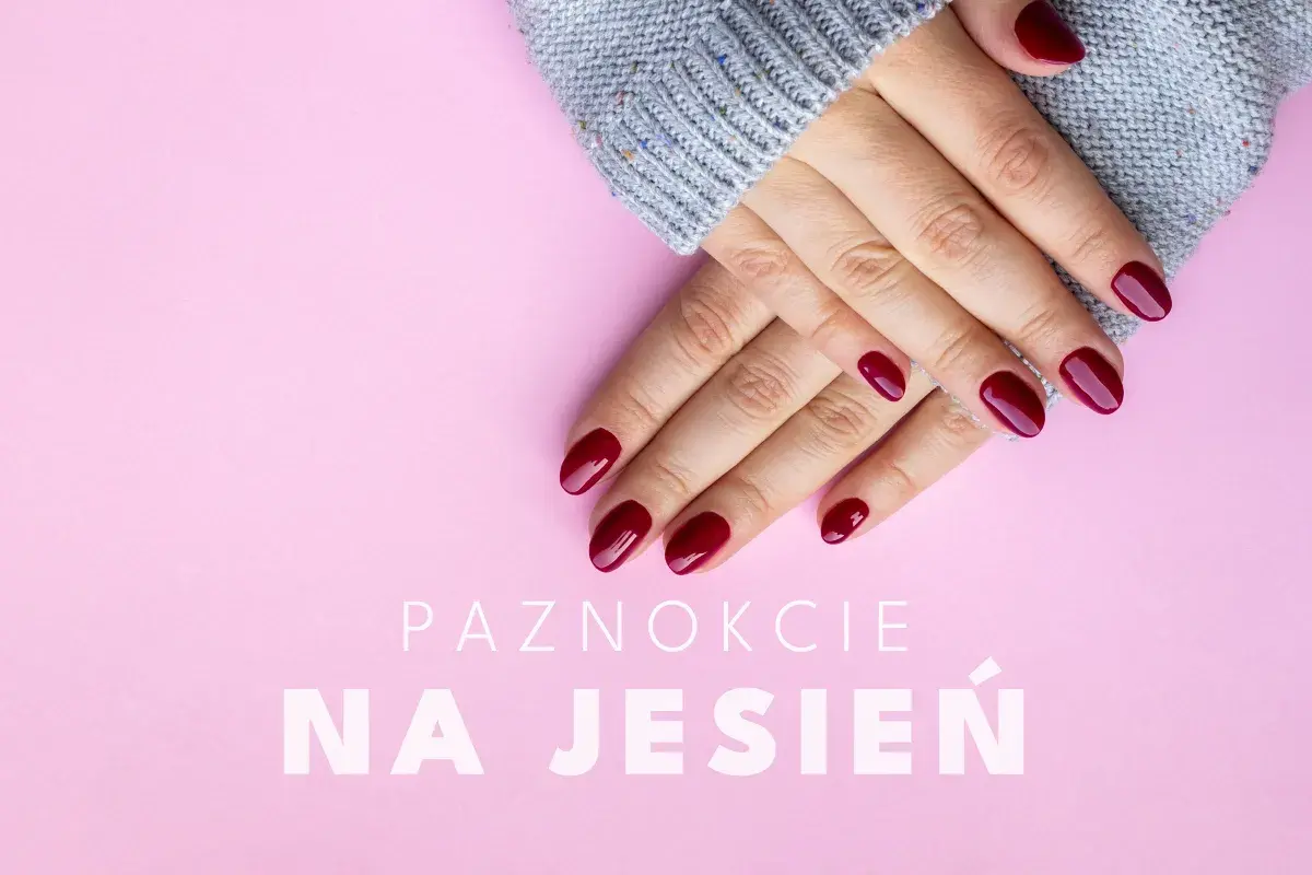 Dłonie w szarym swetrze z idealnymi, bordowymi paznokciami na jesień.