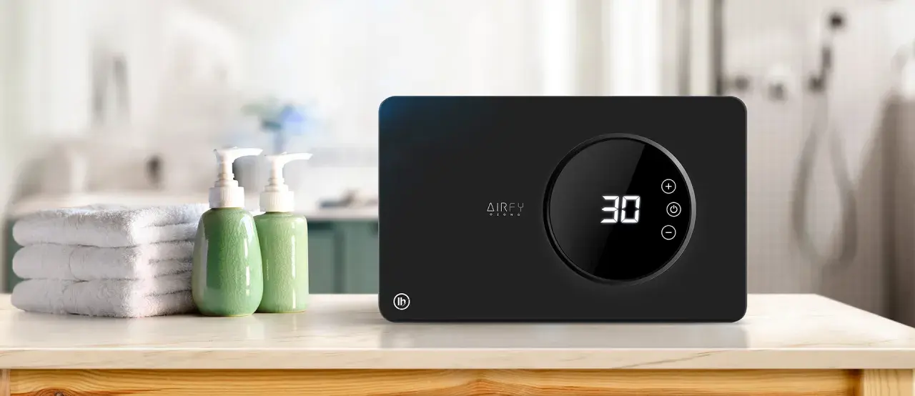 Purificador de aire AIRFY OZONO, con temporizador digital y controles táctiles. Junto a toallas y dispensadores de jabón, ideal para un ambiente fresco.