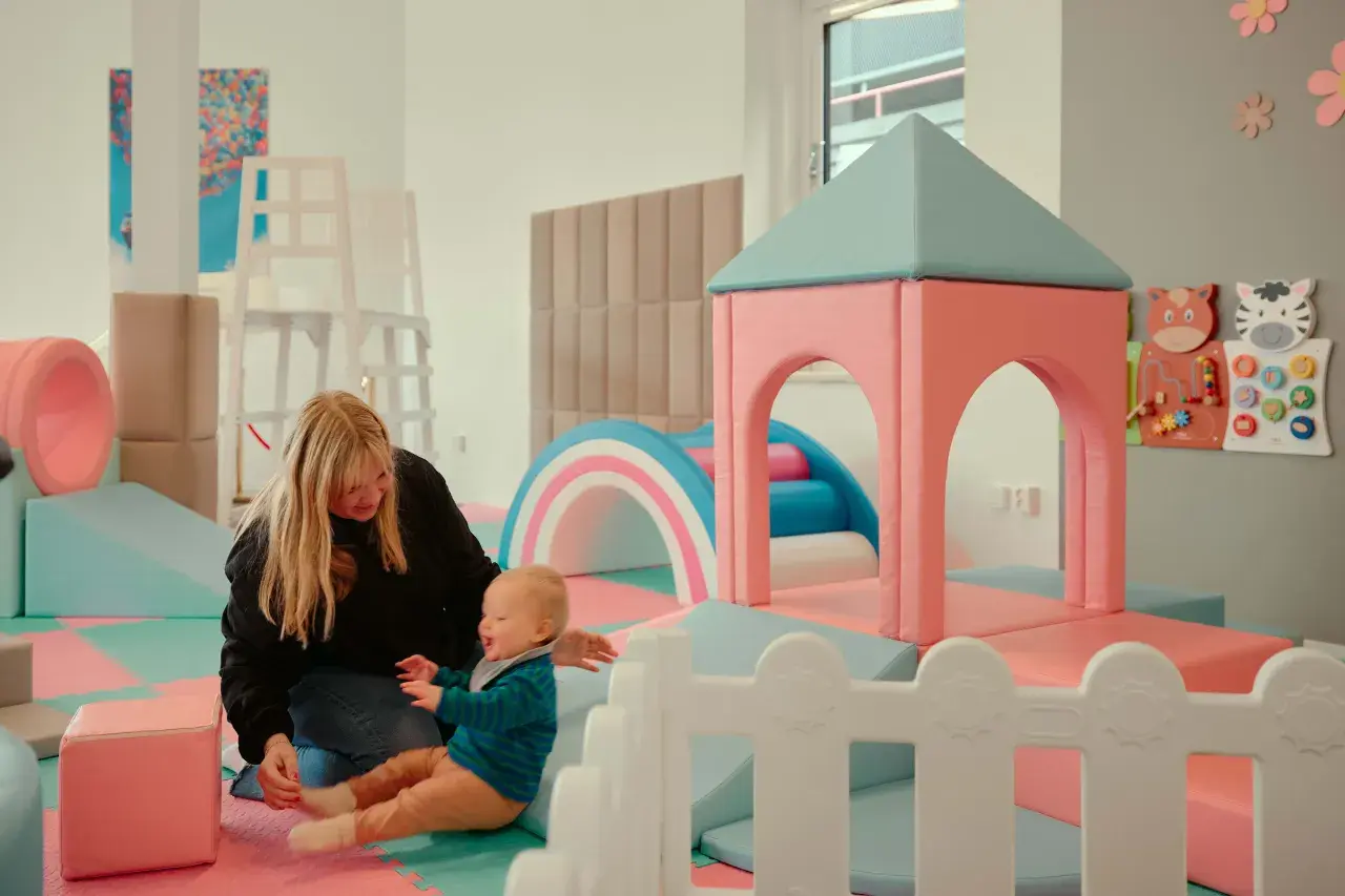 En mamma leker med sitt barn i en lekplats. En rolig och gratis upplevelse för barn i Stockholm.