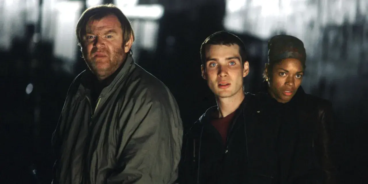 Trzech ocalałych, w tym mężczyzna z groźną miną, przemierzają mroczne ulice w świecie po apokalipsie. To scena z filmu "28 dni później".
