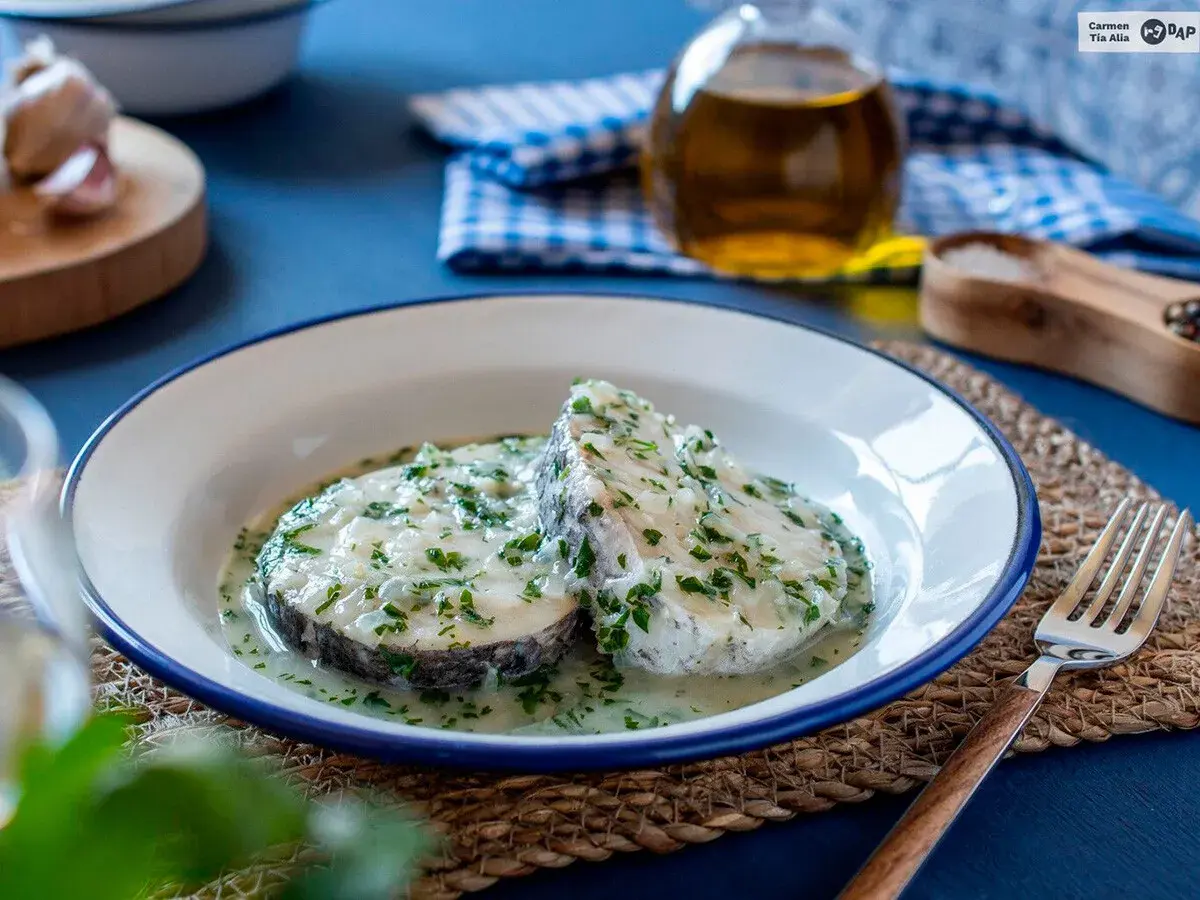 Dos rodajas de merluza en salsa verde, con perejil picado y un toque de ajo.