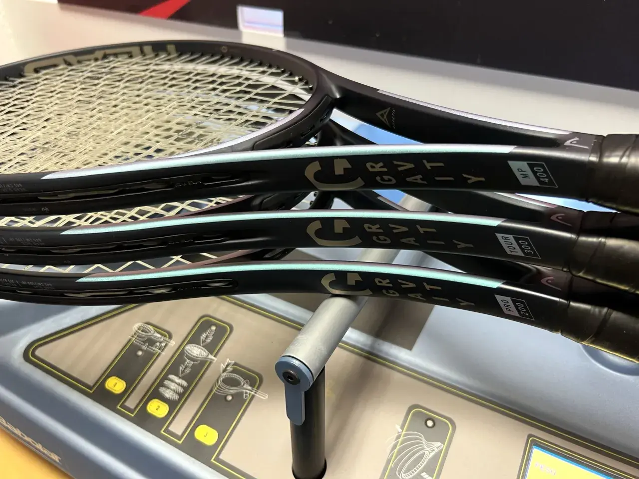 Tre racchette Head Gravity MP, pronte per essere incordate su una macchina Babolat.